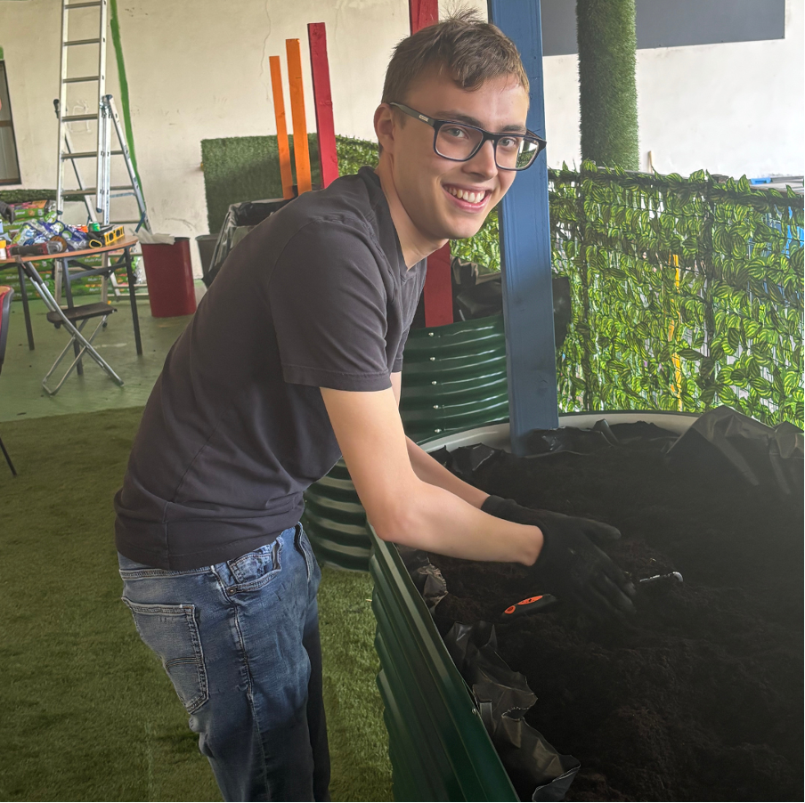 Image of William planting bushes at the ONE Centre community garden