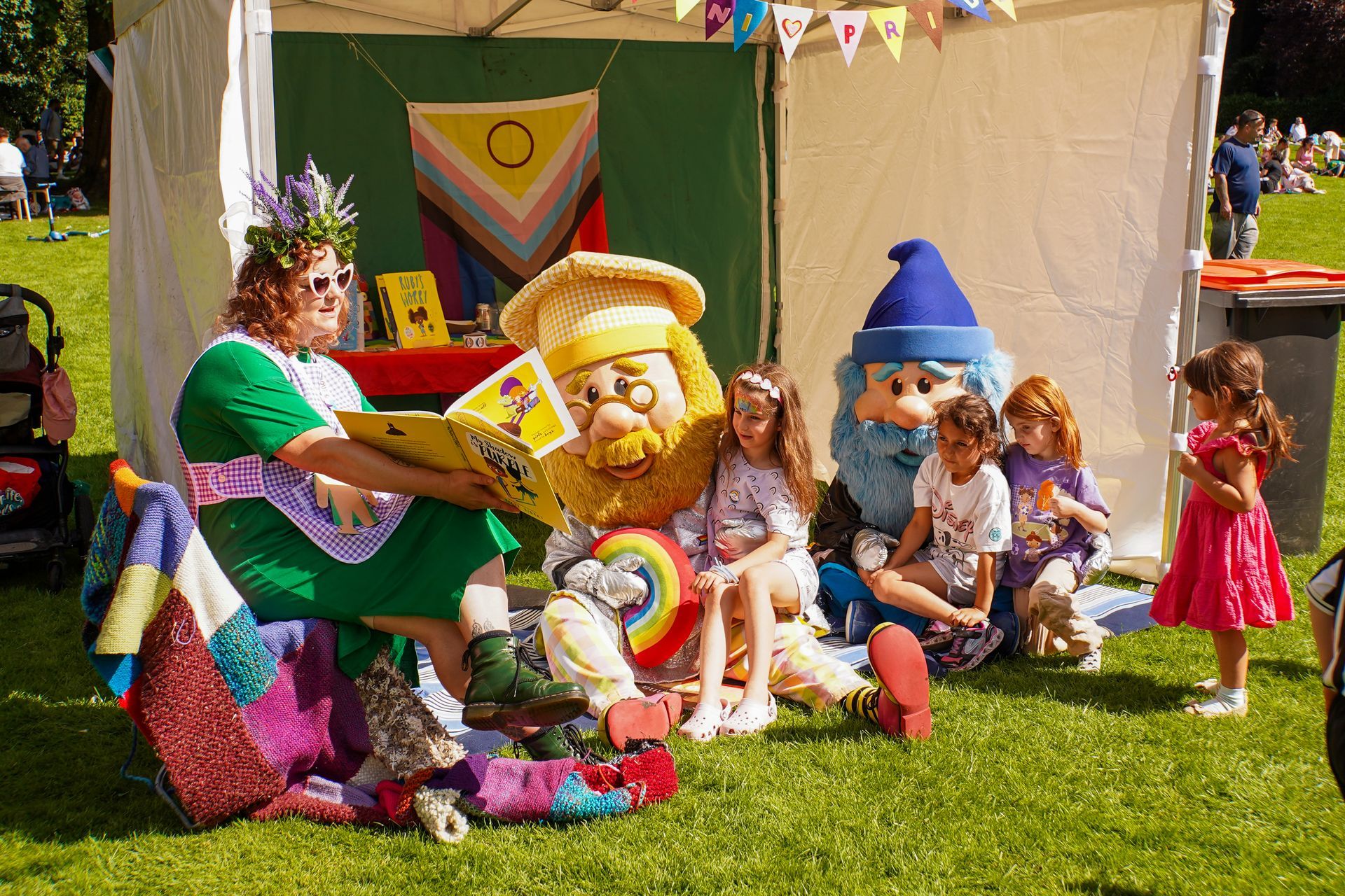 People in costume reading to children at an outdoor event.