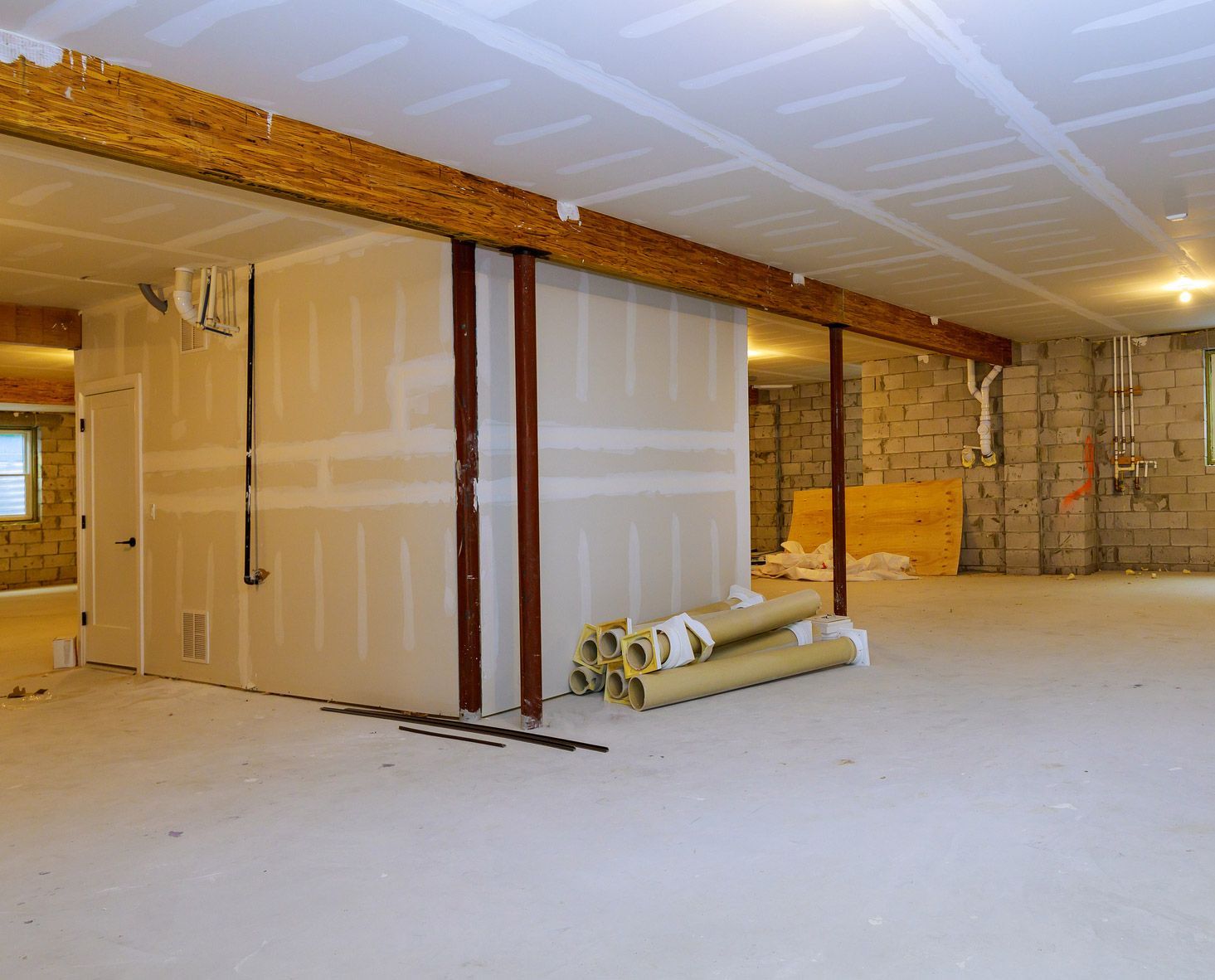 A basement room with a stack of rolls of insulation on the floor