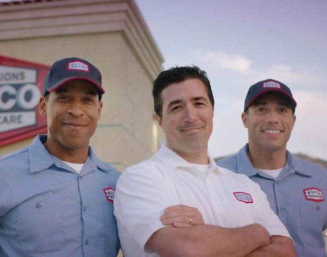Three uniformed workers standing outdoors, smiling in front of a building.