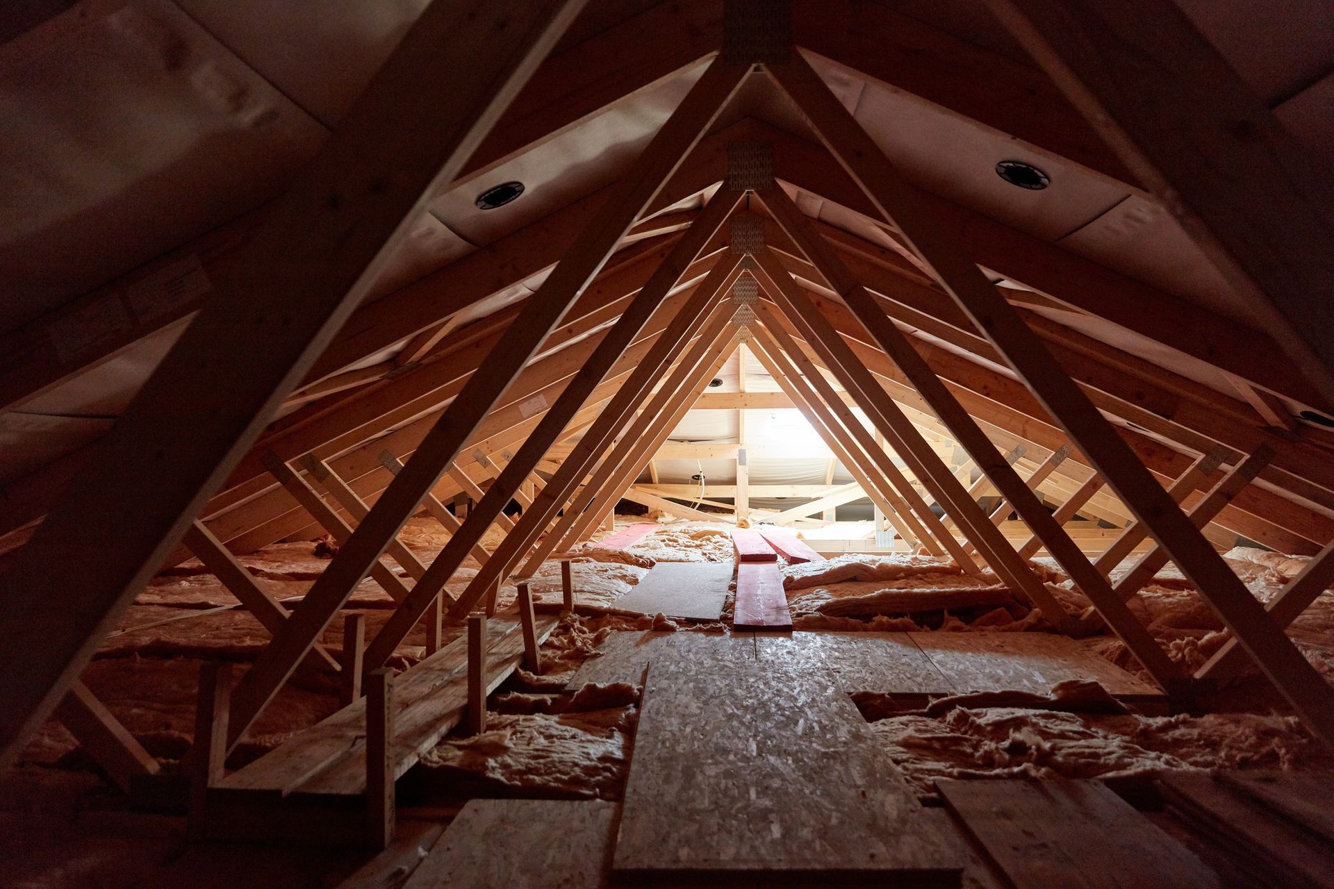 Triangular wooden attic roof framing around a bright opening, with debris on the floor