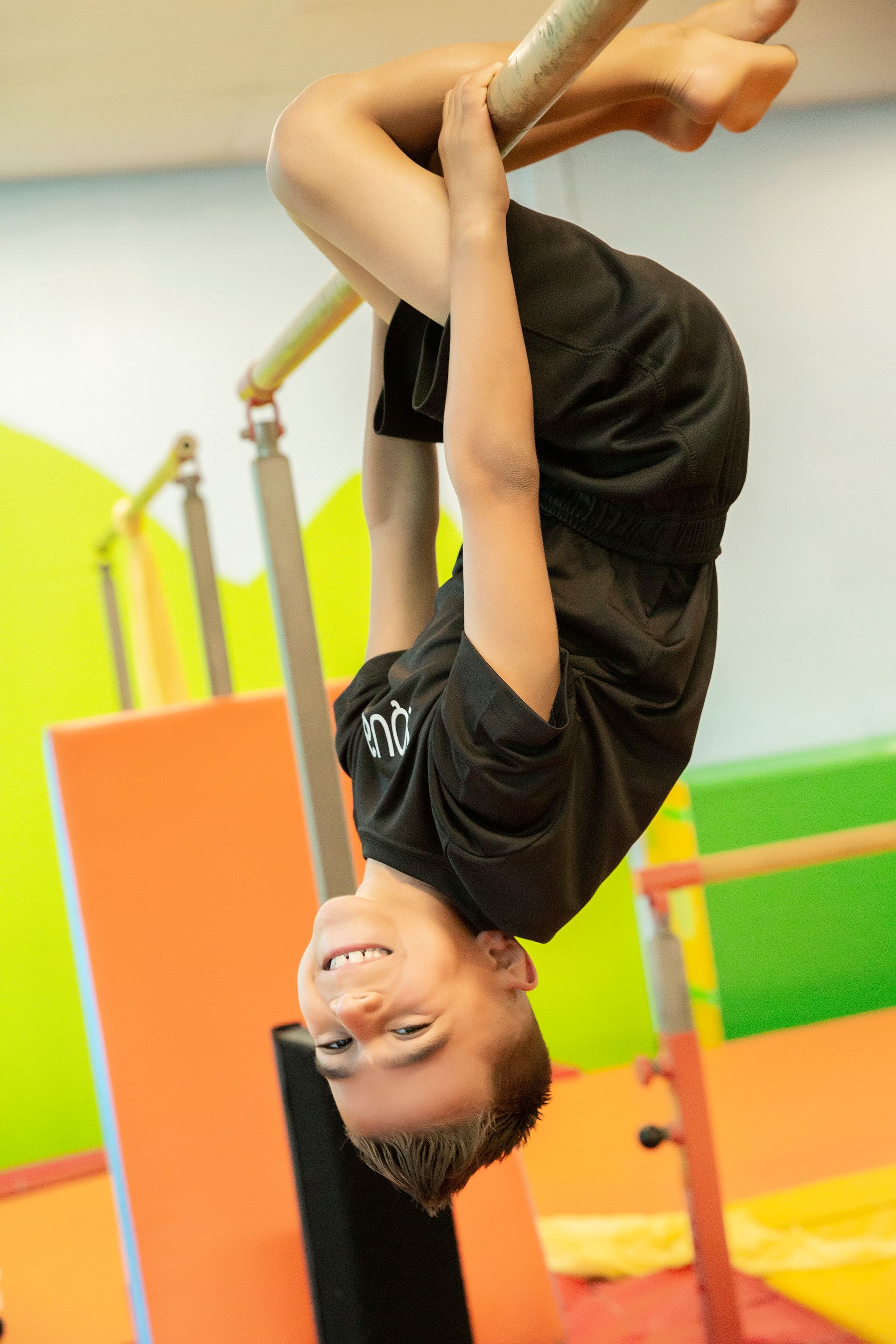 A little girl in a pink leotard is standing on a balance beam.