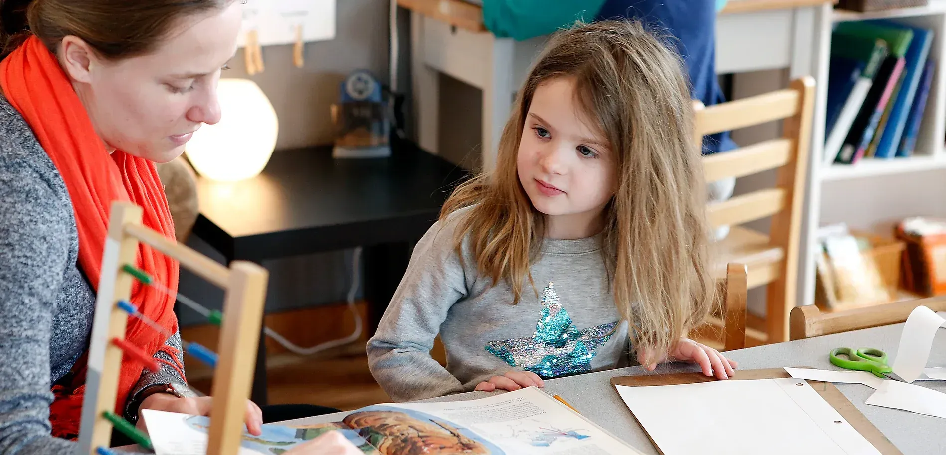 montessori child with guide reading a book