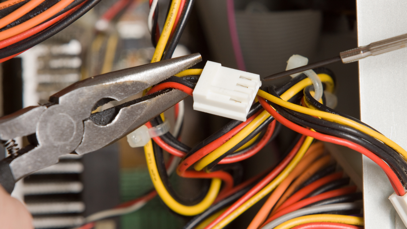 Person installing electrical outlet, hands holding wires and a receptacle, close-up.
