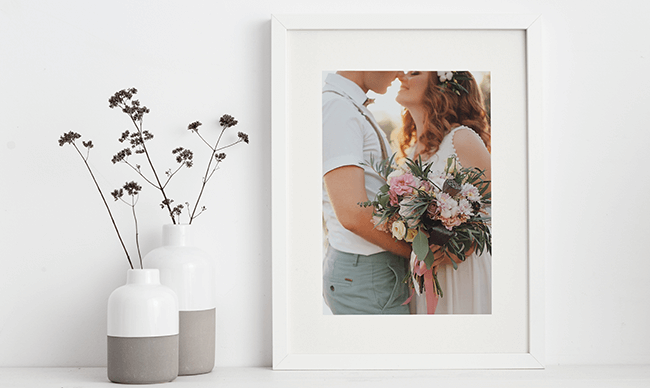 Framed photo of a couple holding a bouquet beside minimalist vases and dried flowers
