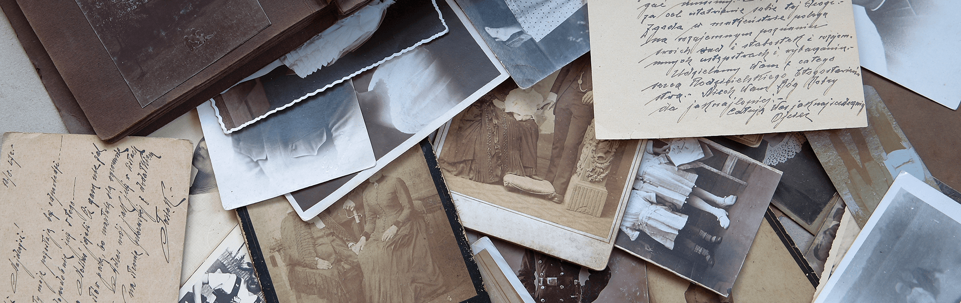 Scattered black-and-white photo prints and handwritten notes on a wooden surface