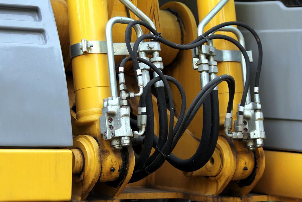 A Close up Of Hydraulic Cylinders on A Yellow Construction Vehicle — Alice Hosetech & Industrial Supplies in Ciccone, NT