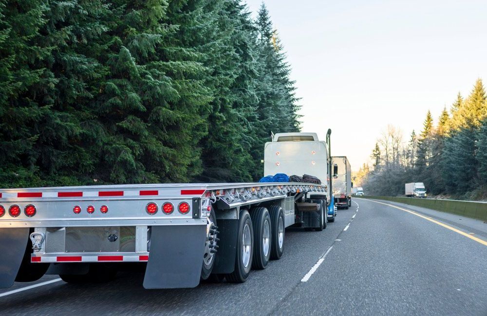 A Semi Truck Is Driving Down a Highway Next to A Forest — Alice Hosetech & Industrial Supplies in Ciccone, NT