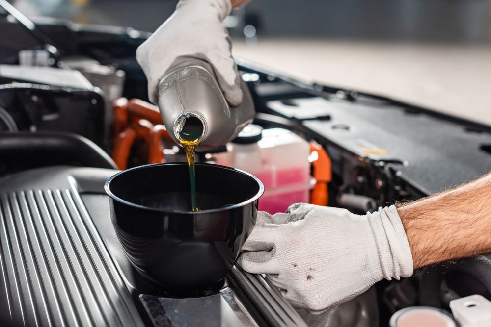 A Man Is Pouring Oil Into a Bowl from A Bottle — Alice Hosetech & Industrial Supplies in Ciccone, NT