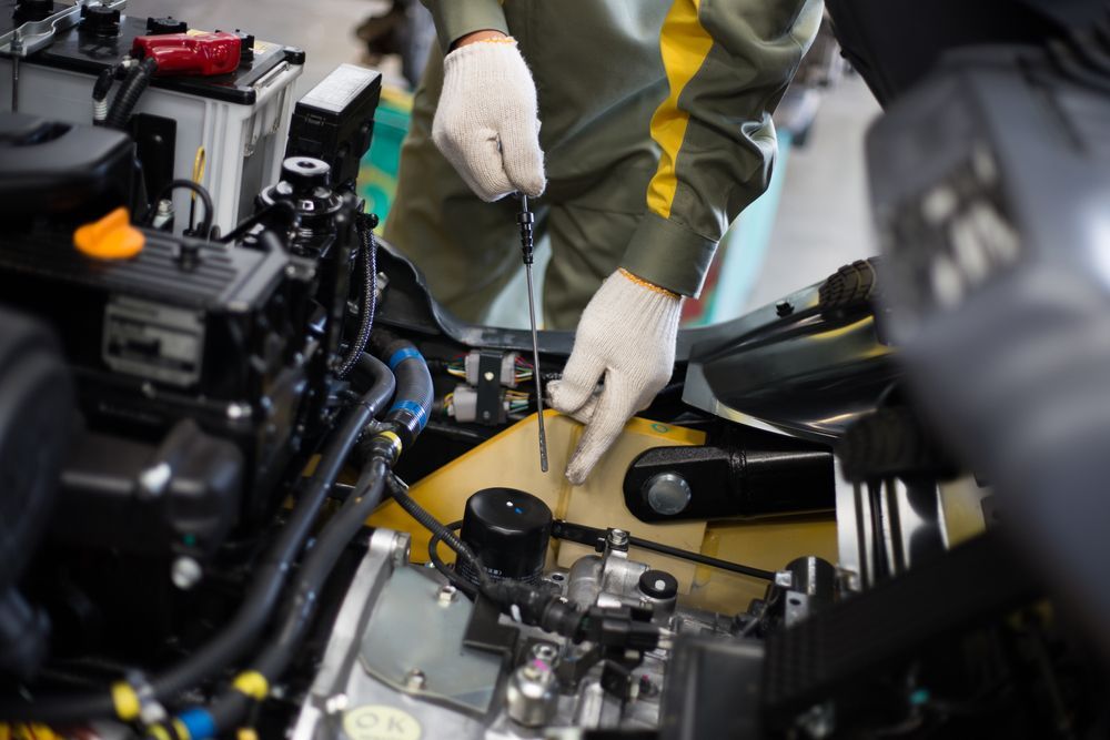 A Man Is Working on A Car Engine with A Screwdriver — Alice Hosetech & Industrial Supplies in Ciccone, NT