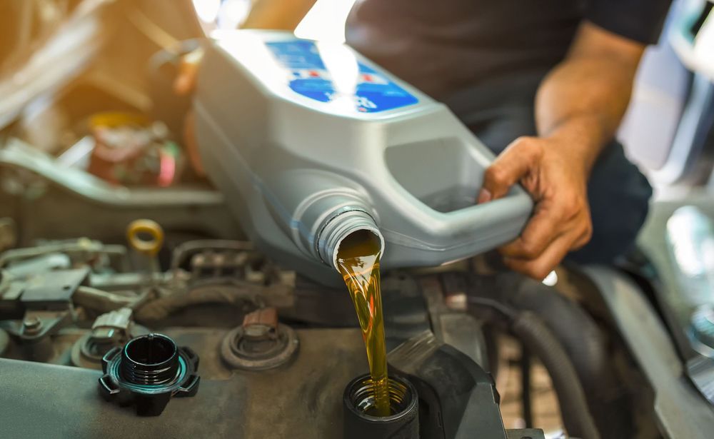 A Man Is Pouring Oil Into a Car Engine — Alice Hosetech & Industrial Supplies in Ciccone, NT