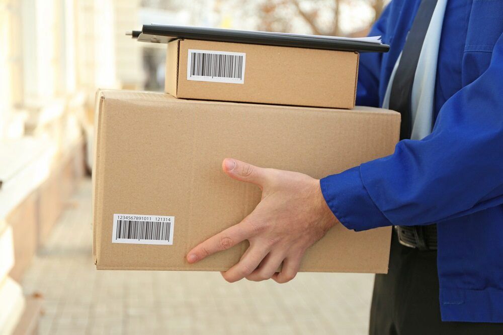A Delivery Man Is Holding A Stack Of Cardboard Boxes — CC Couriers FNQ in Portsmith, QLD