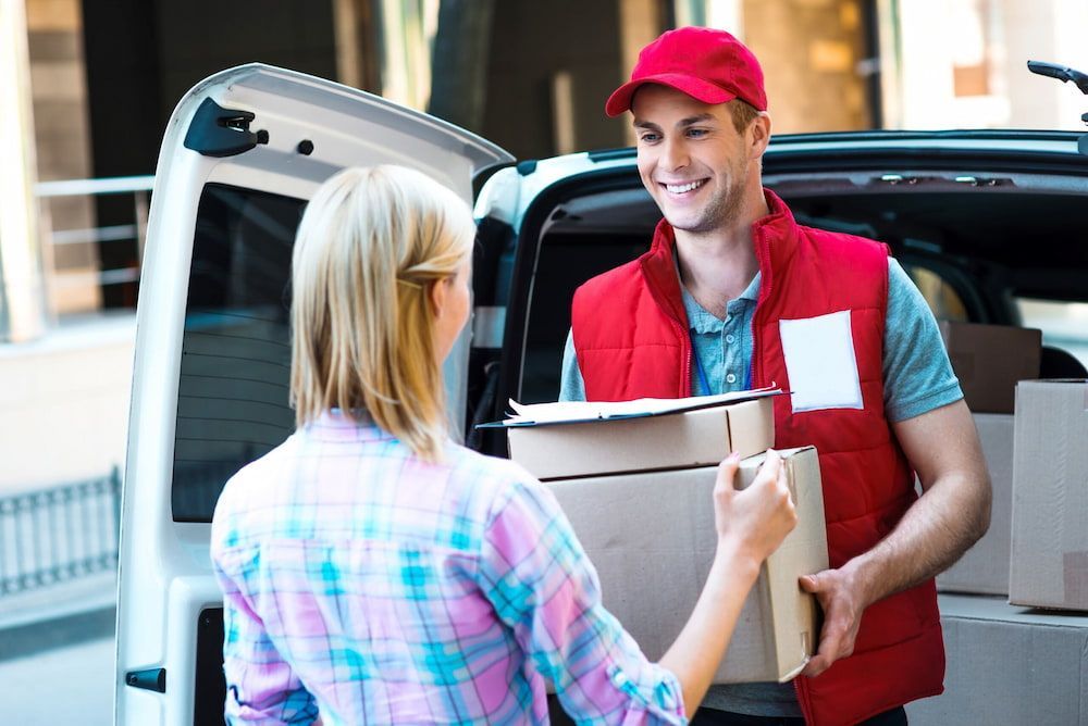 A Delivery Man Is Handing A Package To A Woman — CC Couriers FNQ in Northern Beaches, NSW