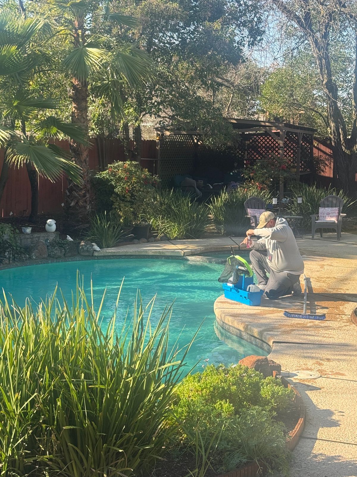 Pool technician testing water chemistry during a weekly service visit in Sacramento