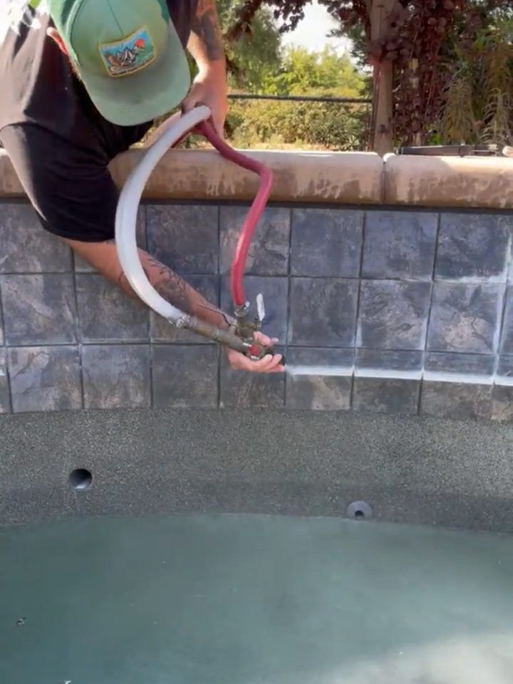 Blast nozzle moving along slate pool tile with the white calcium line ahead of it and clean tile behind it