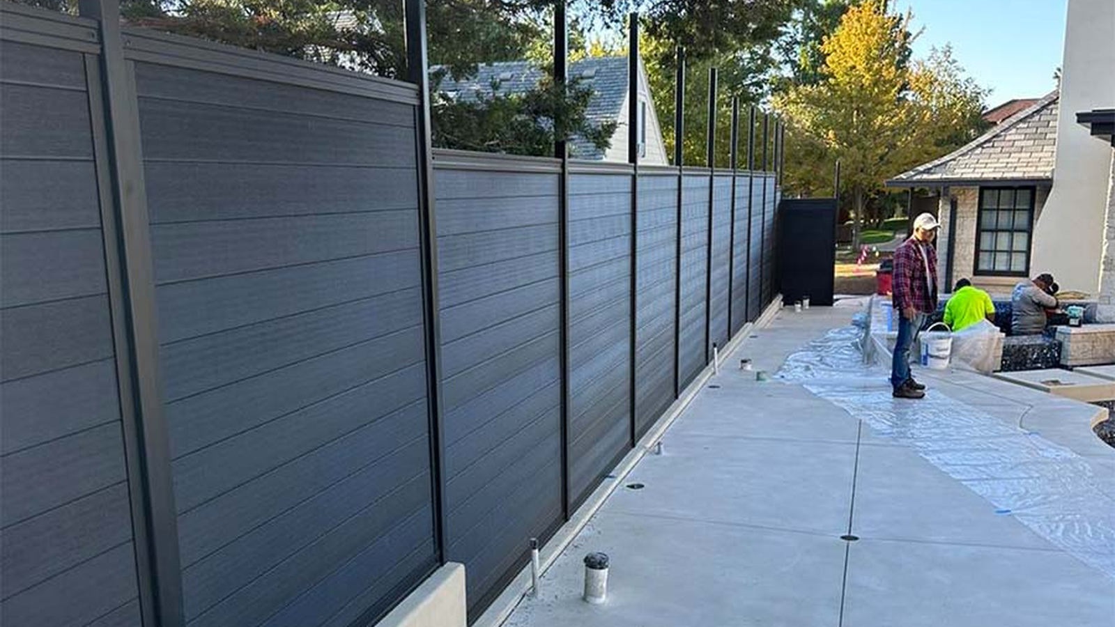 Man kneeling, building a yellow fence, outdoor setting.