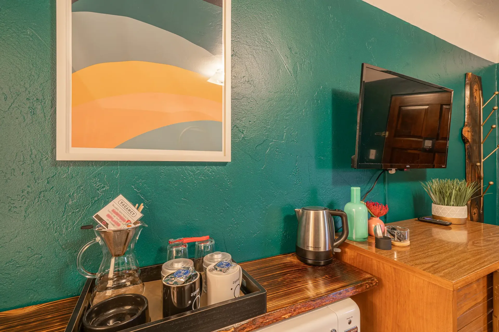 A kitchen counter with a picture on the wall and a television.