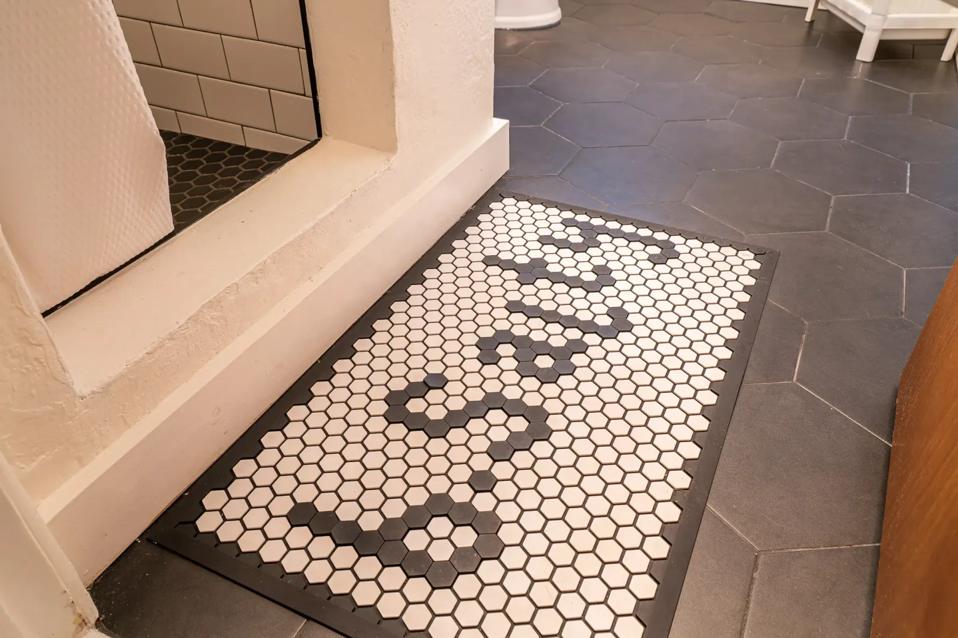 A black and white rug on the floor in a bathroom.