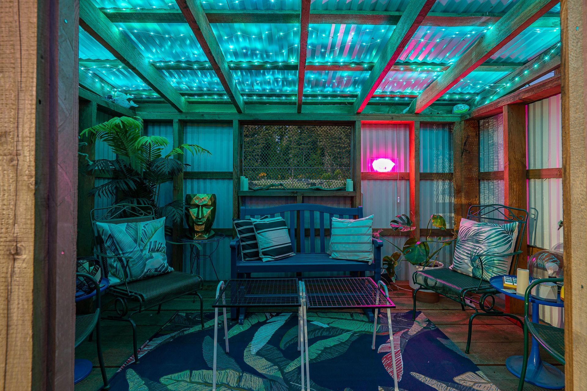 A living room with a couch , table , chairs , and lights on the ceiling.