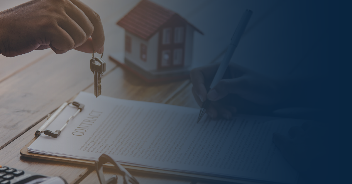 A hand holds keys over a contract on a desk next to a miniature house model as someone signs the document.