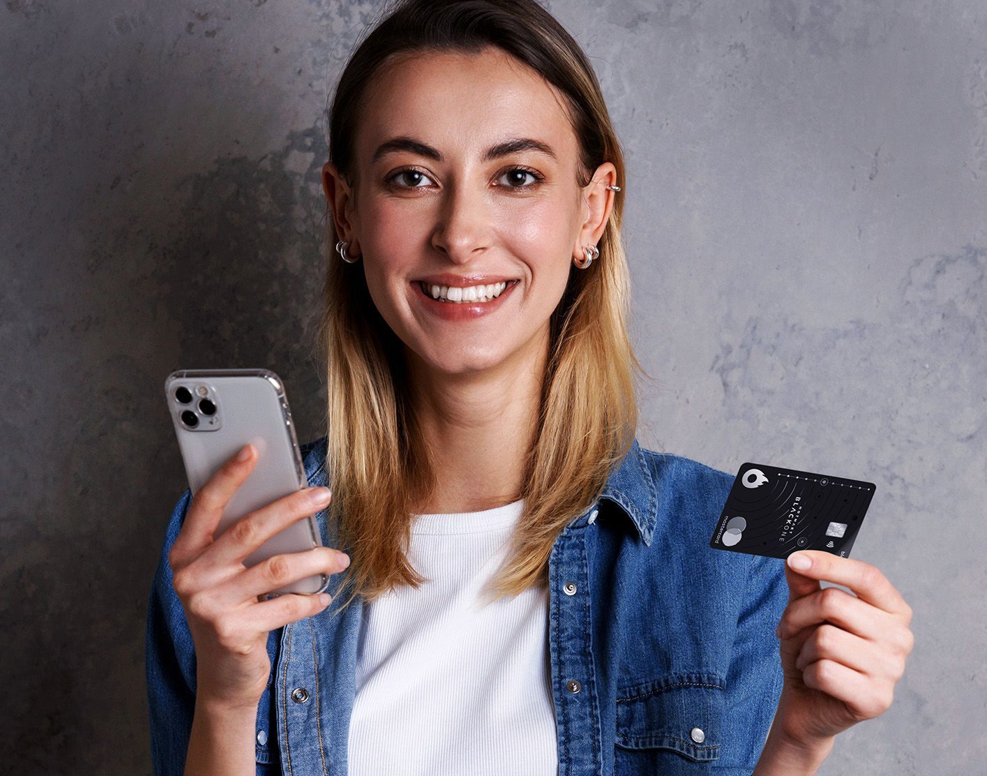 Uma mulher está segurando um cartão de crédito e um celular.