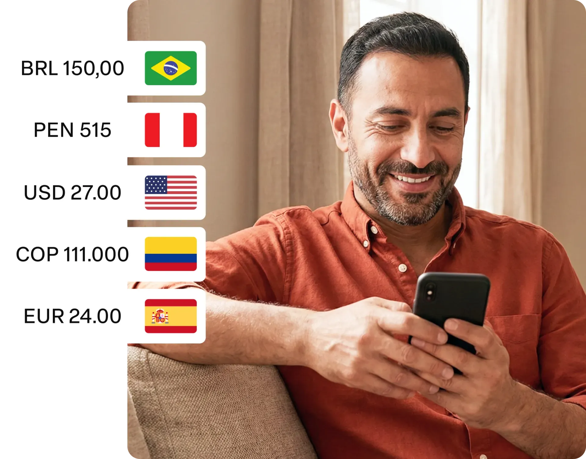 Homem sorrindo sentado em um sofá enquanto usa um telefone, com uma lista de moedas e bandeiras ao lado dele.