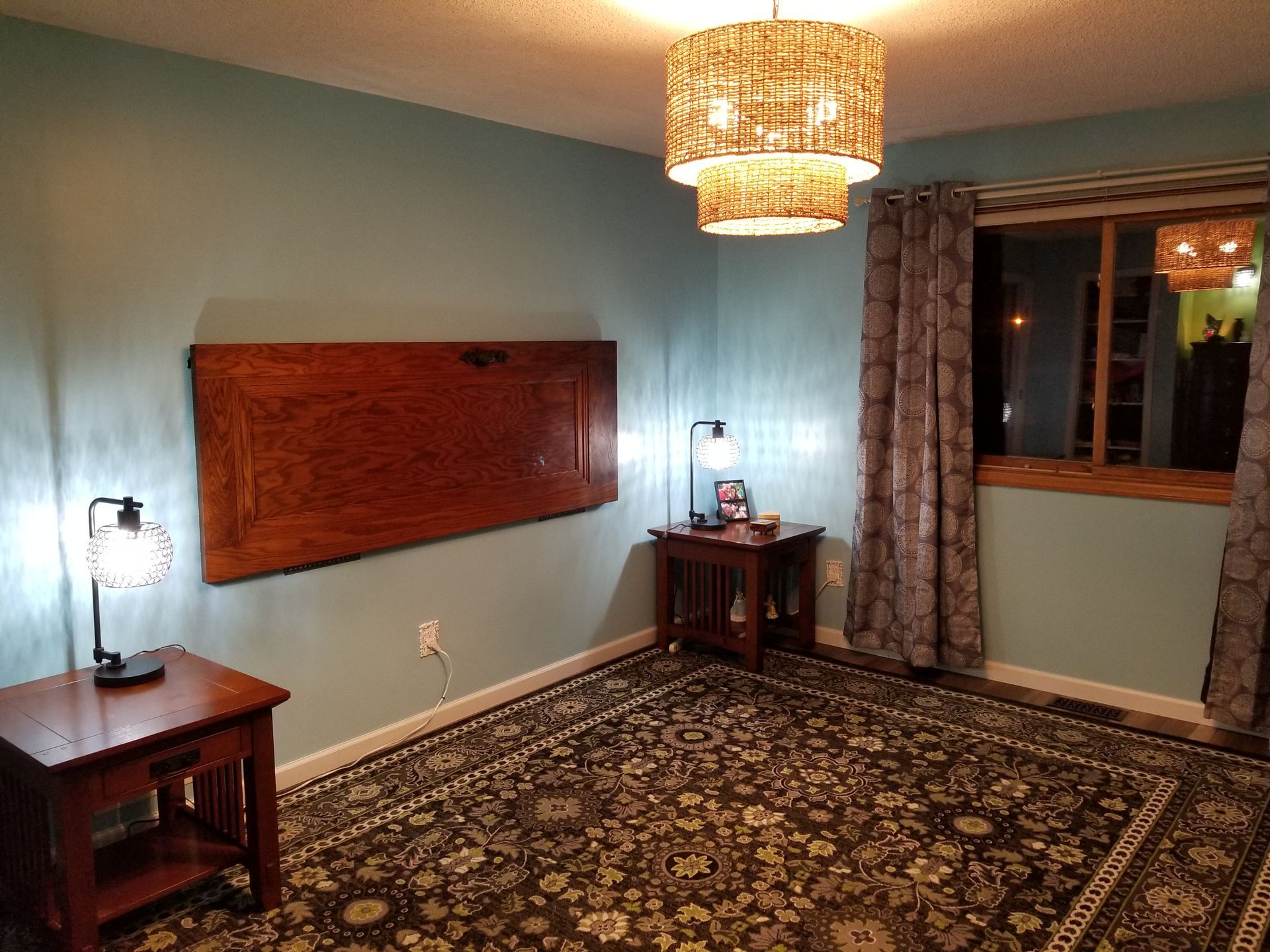 Room with blue walls, ornate rug, wooden tables, and a large wooden wall hanging.