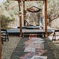 Outdoor rustic aisle with rugs leading to a decorated wedding altar under a wooden pergola