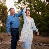 Two people outdoors, smiling and raising clasped hands in a celebratory pose.