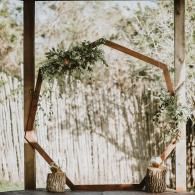 Wooden geometric arch decorated with greenery in a rustic outdoor setting