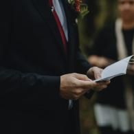 Person in a dark suit holding a paper booklet at an event
