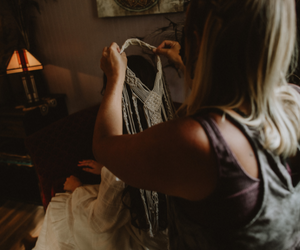 Person holding up a white dress in a warmly lit room with a lamp