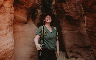 Traveler smiling in a red sandstone canyon, wearing a green shirt and backpack