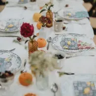 Elegant dining table set with white linens, floral centerpieces, and patterned plates