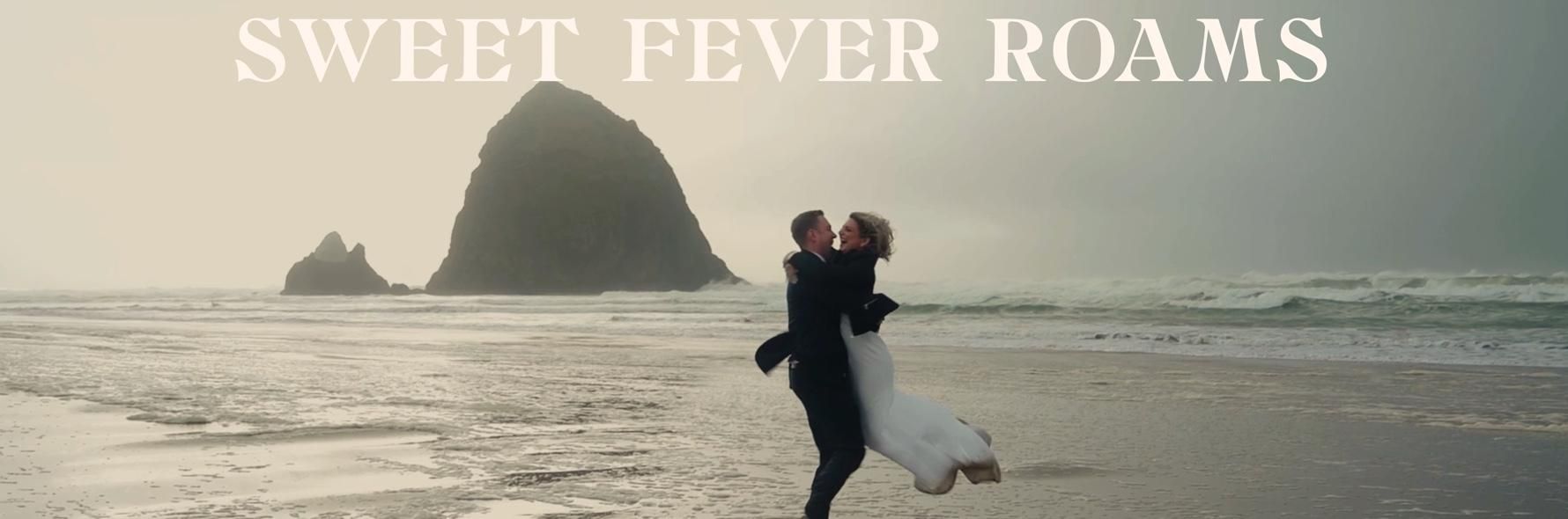 Couple embracing on a beach at sunset with a large sea stack; text reads “SWEET FEVER ROAMS”