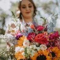 Woman holding a colorful bouquet of roses and sunflowers outdoors