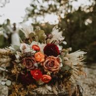 Bouquet of roses in warm orange, red, and cream tones against a blurred outdoor background