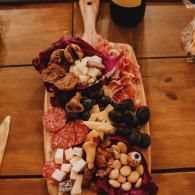 Charcuterie board with meats, cheeses, crackers, grapes, and nuts on a wooden table