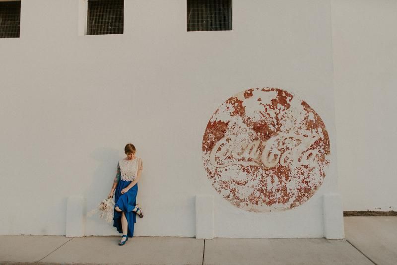 Person leaning against a white wall beside a large red circular mural.