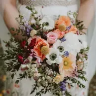 Bride holding a pastel bouquet of white, pink, peach, and coral flowers