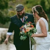 Couple walking outdoors, bride holding a colorful bouquet in a garden setting