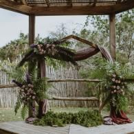Floral-decorated wedding arch with draped fabric in an outdoor garden setting