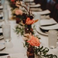 Elegant banquet table with white linens, glassware, and peach floral centerpieces at a formal event