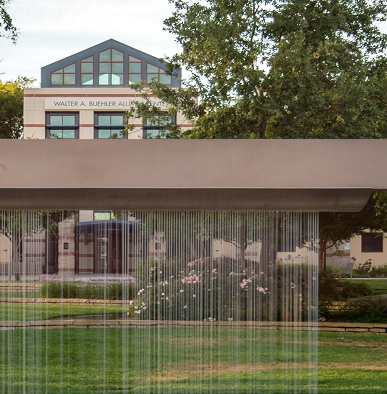 A water fountain curtain in a park with a blurred building named