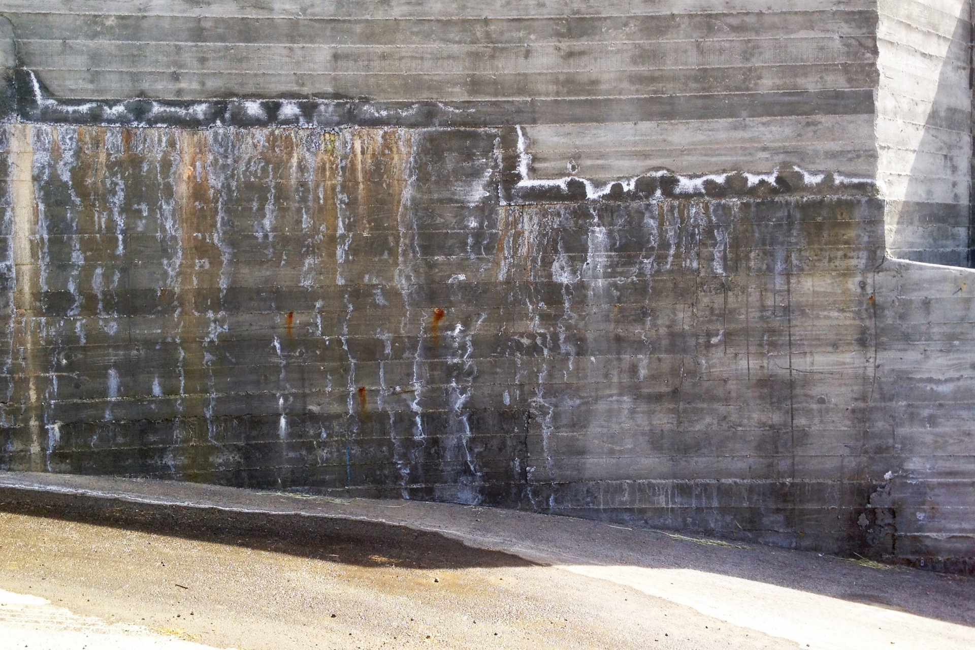 Concrete wall with water stains and white residue.