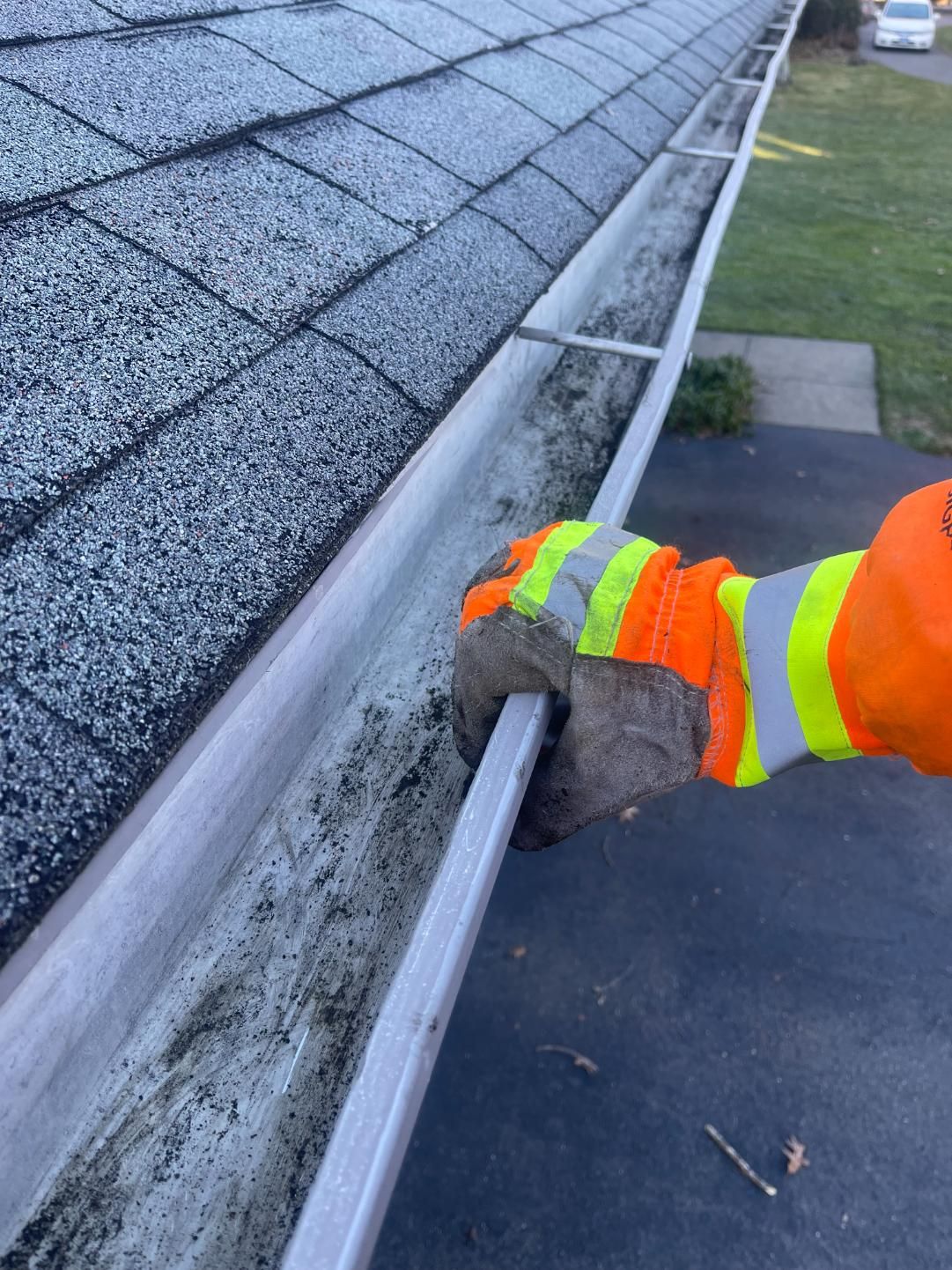 A person is cleaning a gutter on a roof.