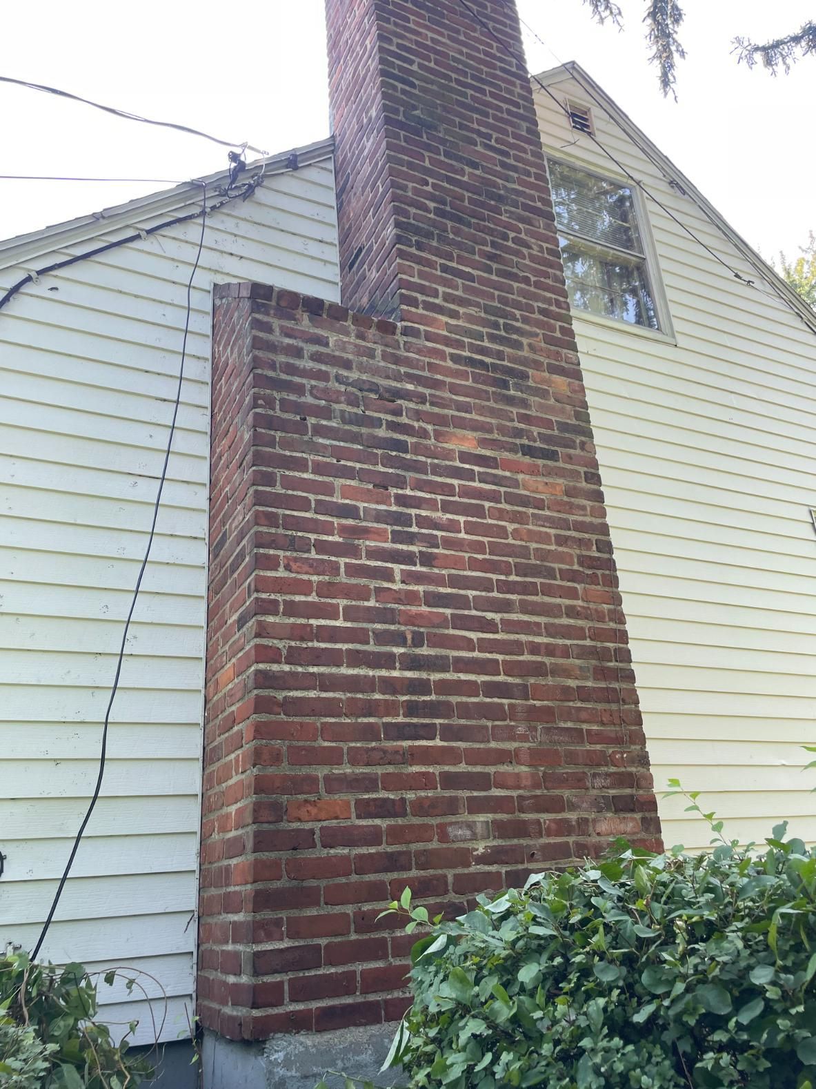A brick chimney on the side of a white house.