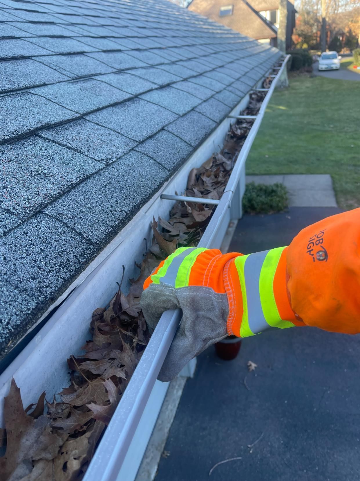 A person is cleaning a gutter with leaves on it.