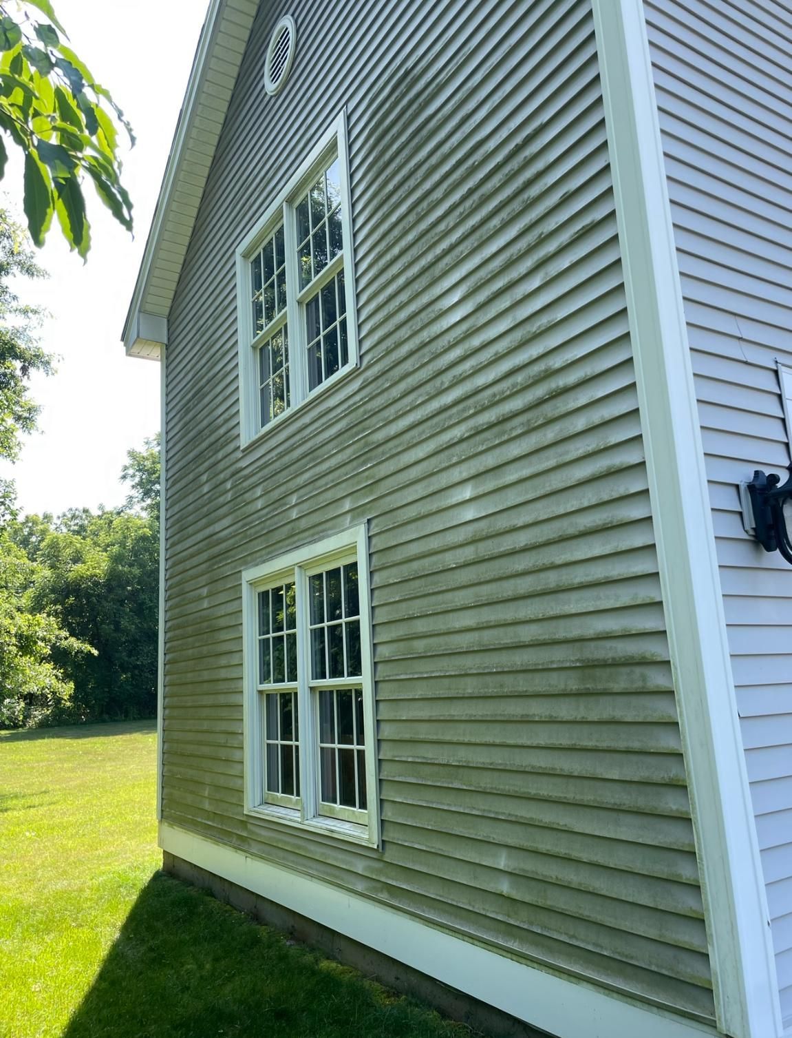 A large house with a lot of windows is sitting on top of a lush green field.