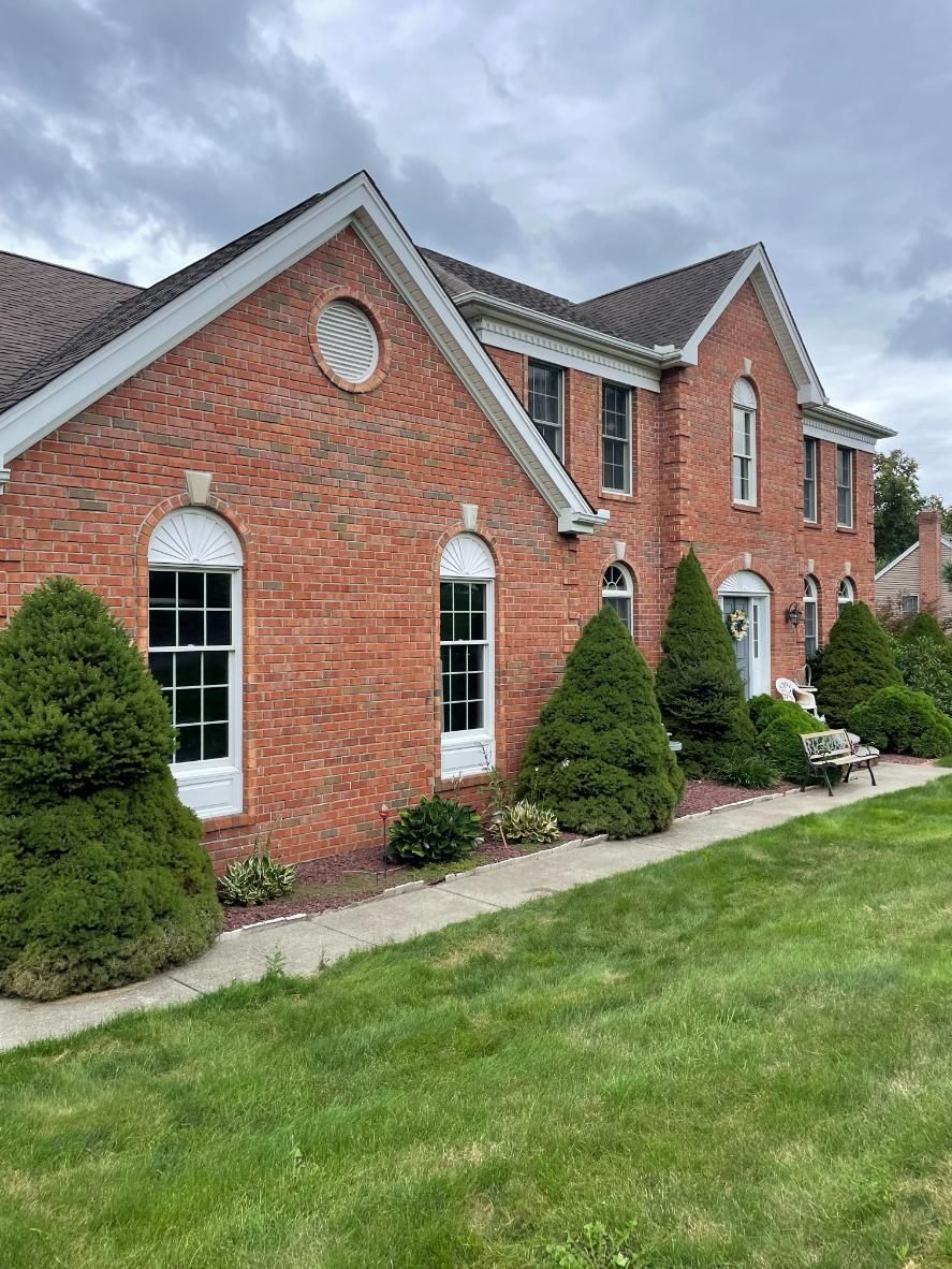 A large brick house with a lush green lawn in front of it.